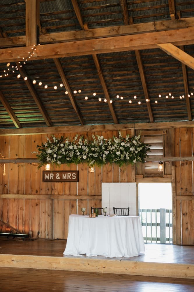 A sweetheart table for two set at the front of the barn.